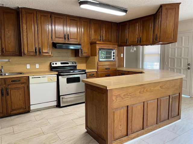 kitchen featuring stainless steel range with electric stovetop, dishwasher, a textured ceiling, a center island, and sink