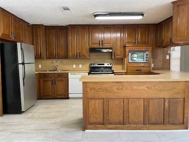 kitchen with a textured ceiling, appliances with stainless steel finishes, and sink