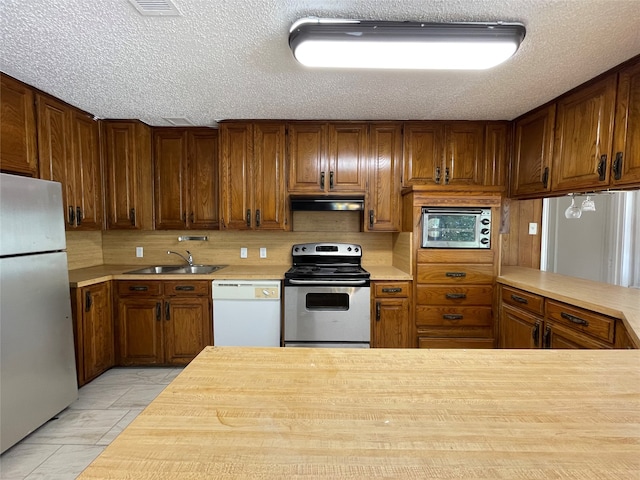 kitchen featuring decorative backsplash, light tile patterned floors, stainless steel appliances, a textured ceiling, and sink