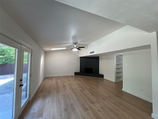 unfurnished living room with light hardwood / wood-style flooring, built in features, ceiling fan, a fireplace, and a textured ceiling