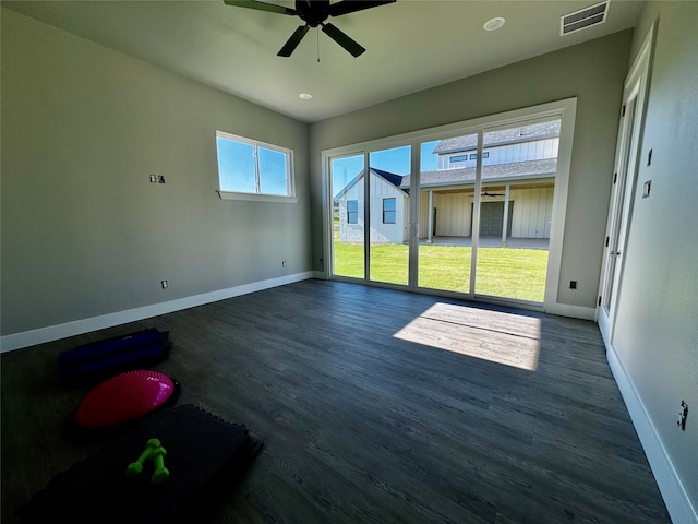 spare room with ceiling fan, dark wood-type flooring, and a wealth of natural light