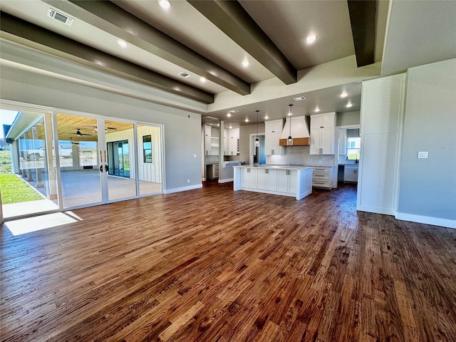 unfurnished living room featuring beamed ceiling and dark wood-type flooring