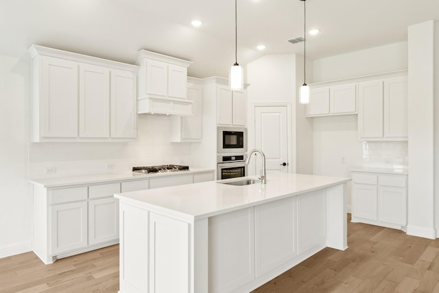 kitchen with a kitchen island with sink, sink, white cabinets, and light wood-type flooring