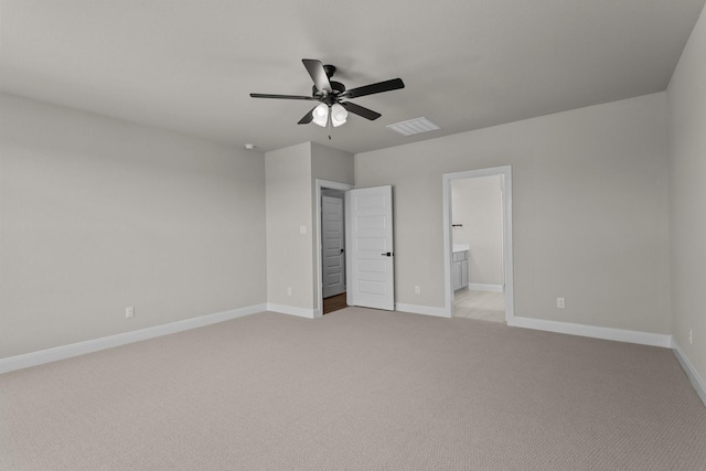 unfurnished bedroom featuring baseboards, ensuite bath, visible vents, and light colored carpet