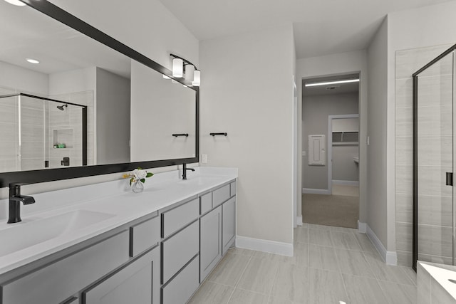 full bathroom with double vanity, a sink, a walk in closet, and a shower stall