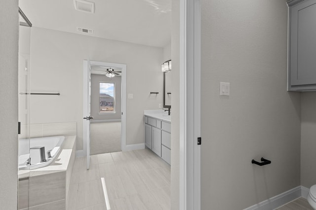 bathroom with a garden tub, visible vents, ceiling fan, vanity, and baseboards