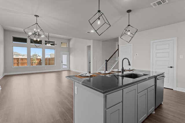 kitchen featuring visible vents, an island with sink, open floor plan, decorative light fixtures, and a sink