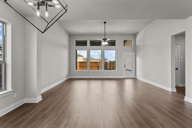 unfurnished living room featuring a ceiling fan, baseboards, and dark wood-style flooring