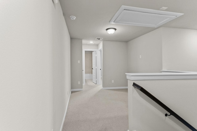 hall with baseboards, light colored carpet, visible vents, and an upstairs landing