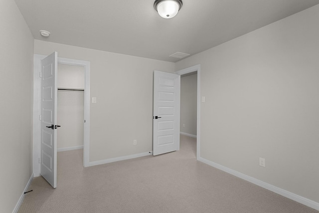 unfurnished bedroom featuring light carpet, a closet, a walk in closet, and baseboards