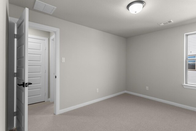 unfurnished room featuring light carpet, visible vents, and baseboards