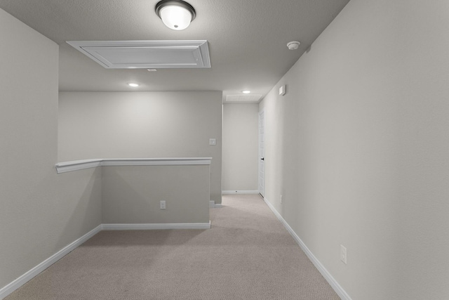 empty room featuring light carpet, baseboards, and a textured ceiling