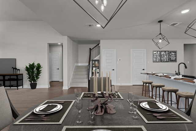 kitchen featuring a breakfast bar, visible vents, dark wood-type flooring, a sink, and baseboards