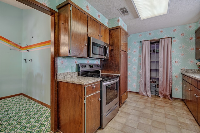 kitchen with a textured ceiling and appliances with stainless steel finishes