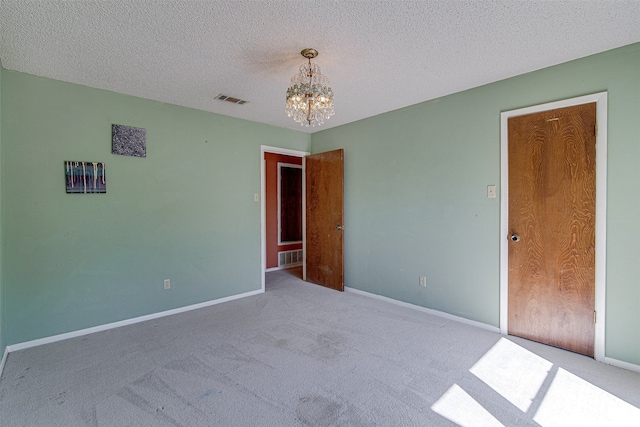 unfurnished bedroom with carpet flooring, a notable chandelier, and a textured ceiling