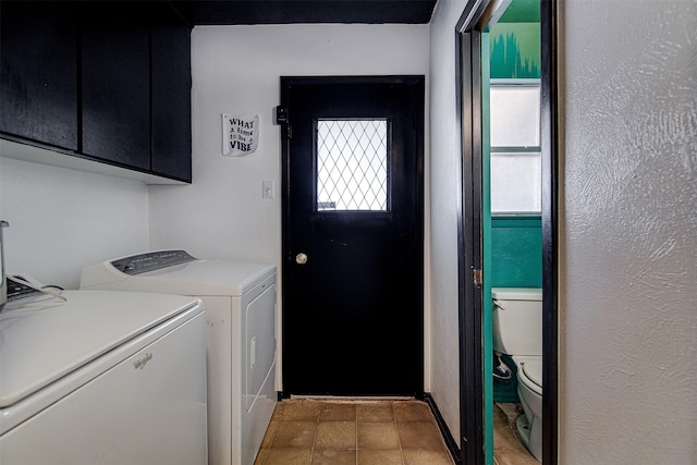 clothes washing area with washer and clothes dryer and cabinets