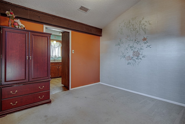 unfurnished bedroom with light colored carpet, lofted ceiling, and a textured ceiling