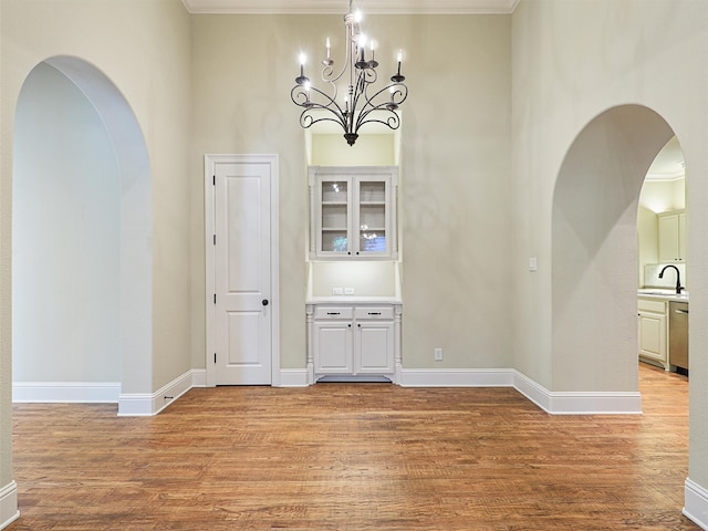 unfurnished dining area with an inviting chandelier, ornamental molding, and light hardwood / wood-style flooring