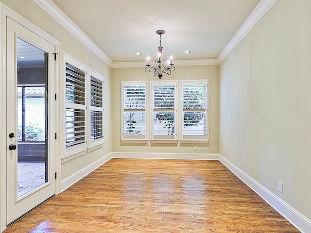 unfurnished dining area with a notable chandelier, light wood-type flooring, and crown molding