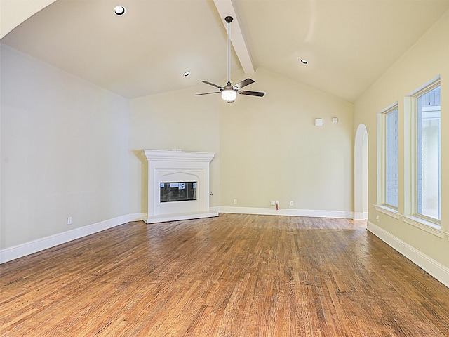 unfurnished living room with ceiling fan, hardwood / wood-style flooring, and vaulted ceiling with beams