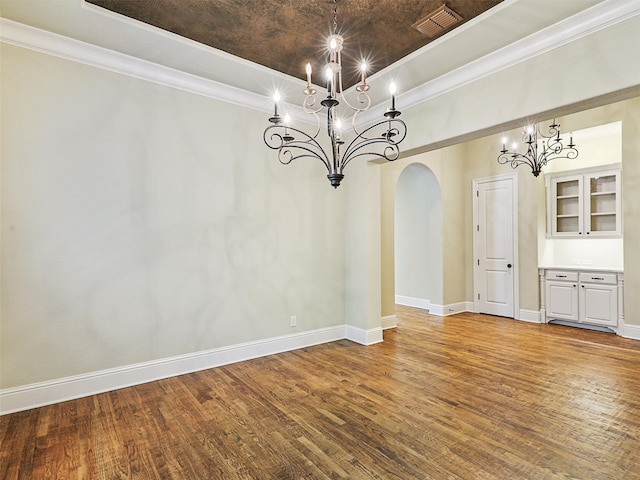 unfurnished dining area with ornamental molding, hardwood / wood-style floors, and an inviting chandelier