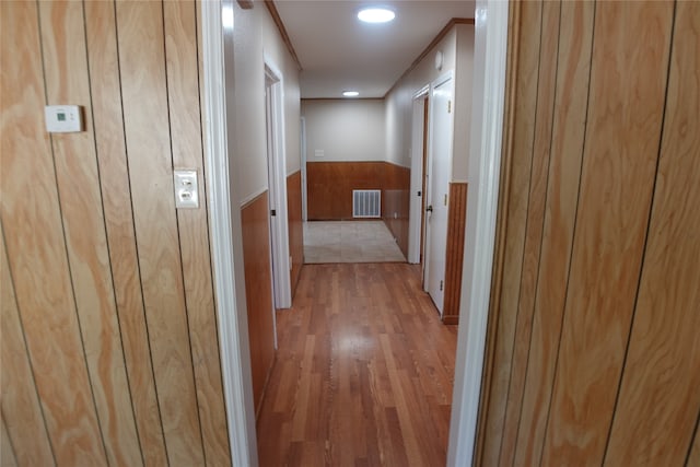 corridor with light hardwood / wood-style floors and ornamental molding