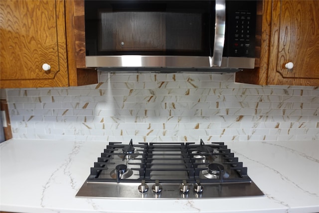 room details featuring light stone counters, appliances with stainless steel finishes, and decorative backsplash