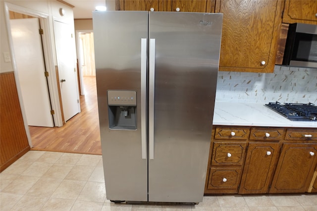 kitchen with appliances with stainless steel finishes, light hardwood / wood-style flooring, and tasteful backsplash