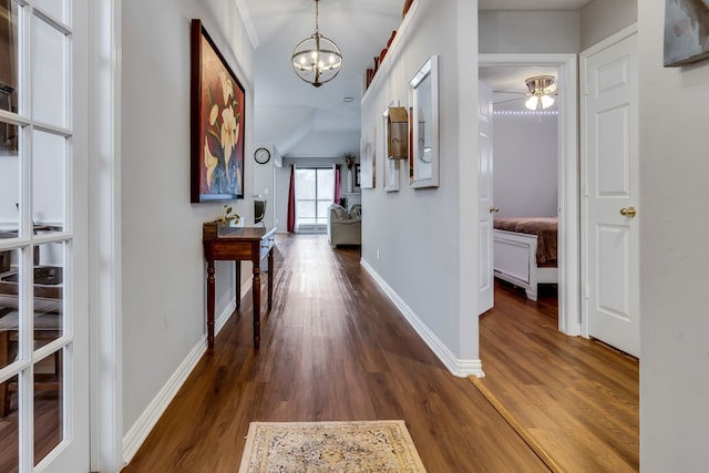 hallway with dark hardwood / wood-style flooring and an inviting chandelier