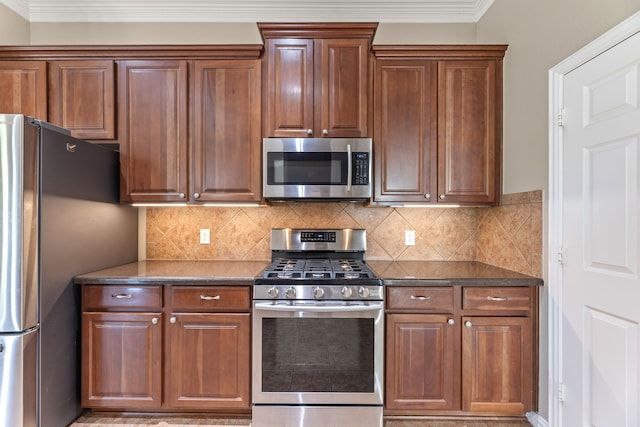 kitchen featuring stainless steel appliances, dark countertops, crown molding, and tasteful backsplash