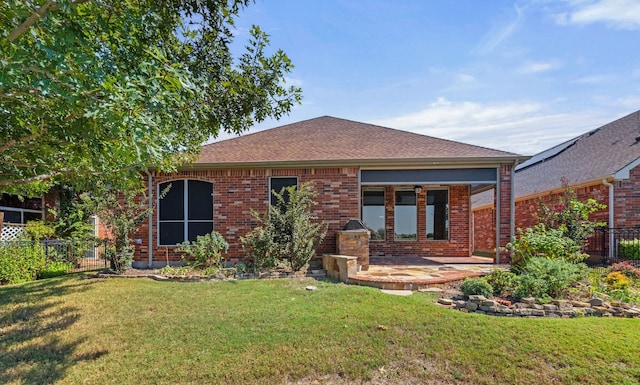 back of house with roof with shingles, fence, a yard, a patio area, and brick siding