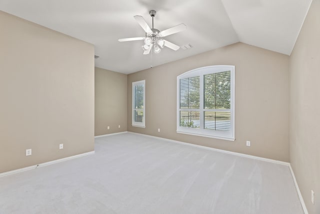 carpeted spare room with vaulted ceiling, ceiling fan, and baseboards