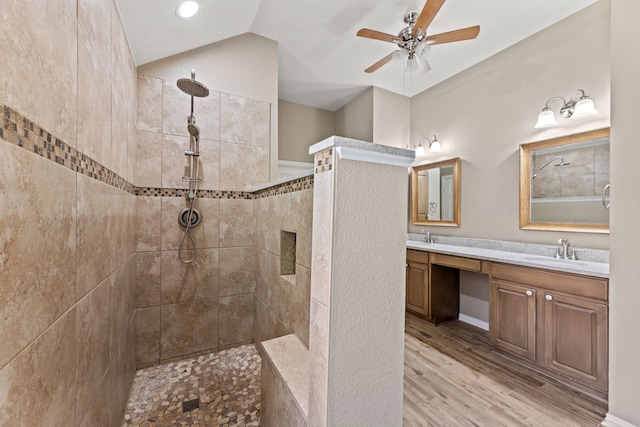 full bath featuring wood finished floors, a sink, vaulted ceiling, double vanity, and walk in shower