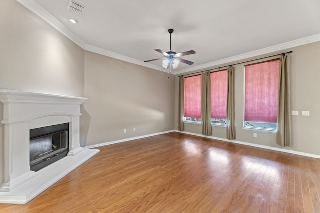 unfurnished living room with ornamental molding, a glass covered fireplace, ceiling fan, and wood finished floors