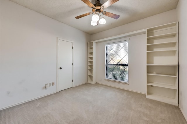 unfurnished bedroom featuring ceiling fan, light colored carpet, and a textured ceiling