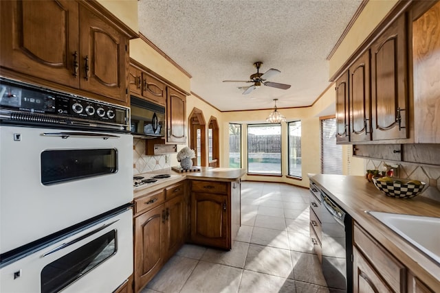 kitchen featuring a textured ceiling, ceiling fan with notable chandelier, decorative backsplash, white appliances, and light tile patterned floors