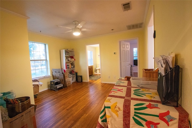 bedroom with ceiling fan, connected bathroom, hardwood / wood-style floors, and crown molding