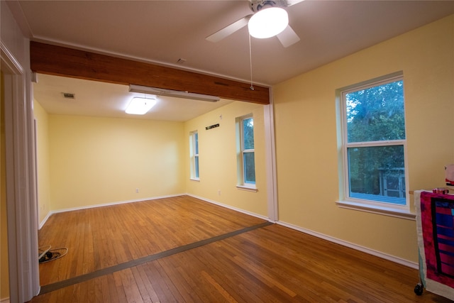 empty room featuring beamed ceiling, ceiling fan, and wood-type flooring