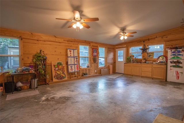 miscellaneous room featuring ceiling fan, wooden walls, concrete floors, and a healthy amount of sunlight