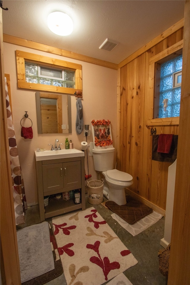 bathroom with vanity, wood walls, and toilet