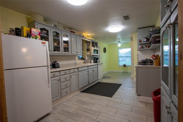 kitchen featuring ceiling fan, decorative backsplash, white appliances, gray cabinets, and a textured ceiling