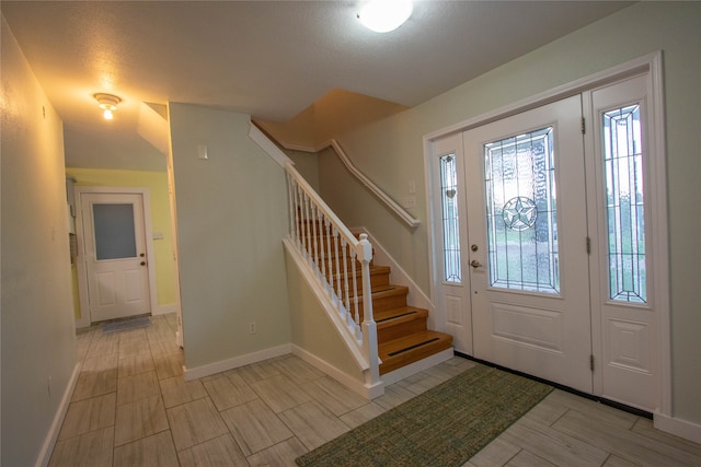 entryway featuring a textured ceiling and vaulted ceiling