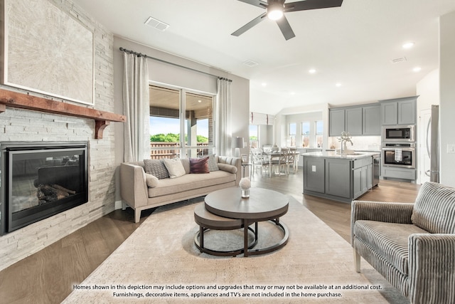 living room with ceiling fan, a fireplace, hardwood / wood-style floors, and sink