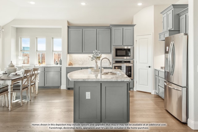 kitchen with stainless steel appliances, sink, lofted ceiling, and light hardwood / wood-style flooring