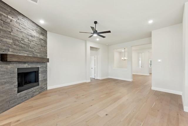 unfurnished living room featuring a fireplace, baseboards, wood finished floors, and ceiling fan with notable chandelier