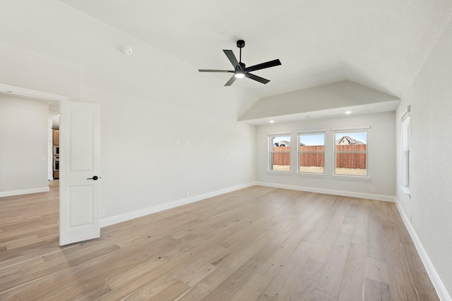 empty room featuring light wood-style floors, lofted ceiling, baseboards, and a ceiling fan