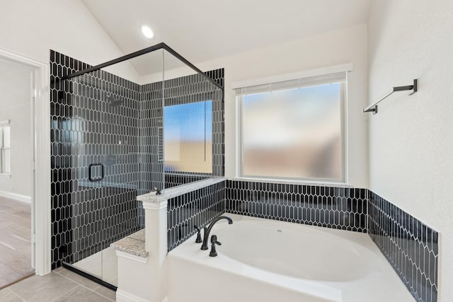 bathroom featuring lofted ceiling, a healthy amount of sunlight, a shower stall, and a bath