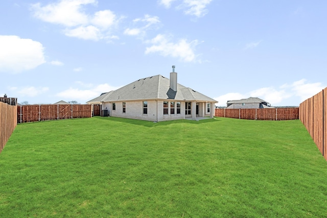 back of property featuring a fenced backyard, a chimney, cooling unit, and a lawn