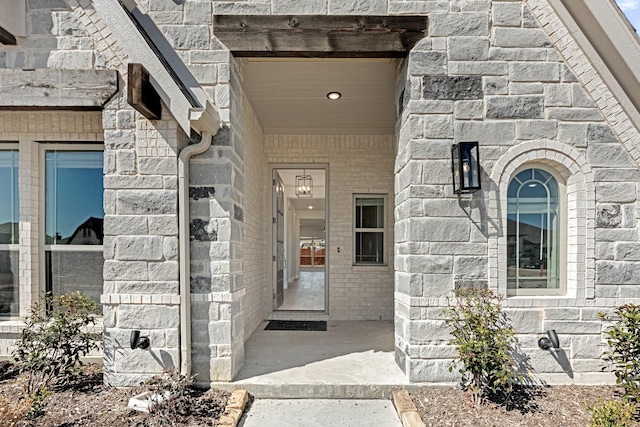 doorway to property featuring stone siding and brick siding