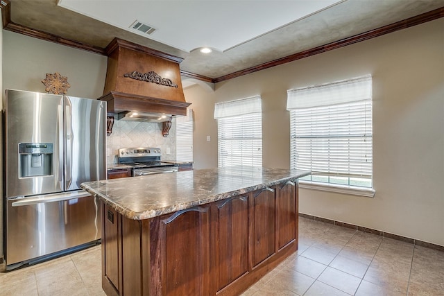 kitchen with custom exhaust hood, a kitchen island, stainless steel appliances, dark stone counters, and crown molding